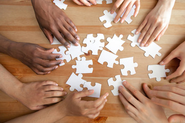 Close up top above view diverse hands assembling puzzles.