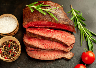 Fresh beef steak, herbs and spices on a stone background