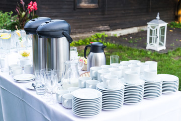 Lot of white porcelain coffee cups and large big thermos on the table in outdoors summer party - Powered by Adobe