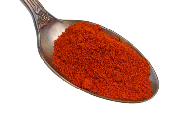 In the old golden spoon there is a small pile of food - ground hot chili pepper spice isolated macro