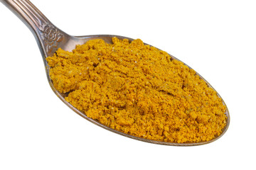 In the old golden spoon there is a small pile of food - ground Indian curry spice isolated macro