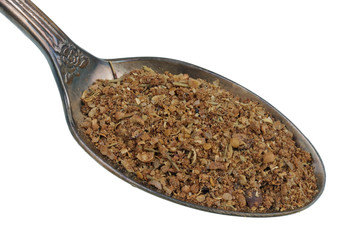In the old golden spoon there is a small pile of food -  dry spices for shish kebab with pepper salt and herbs isolated macro