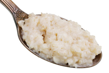 In the old golden spoon there is a small pile of food - oatmeal with milk  isolated macro