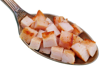 In the old golden spoon there is a small piece  of food -  squar sliced of  smoked fried  ham  pork  meat isolated macro