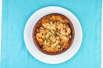 Mediterranean dish, European cuisine. Seafood stew soup- shrimp, fish meat and mushrooms, with cheese and greens