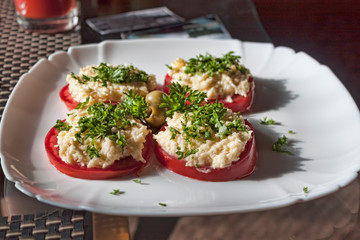 Tomatoes, covered with cheese and sauce, sprinkled with herbs and olives