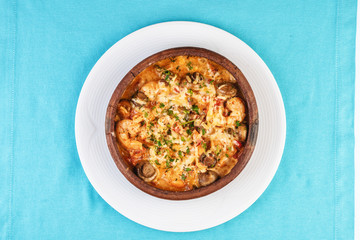 Mediterranean dish, European cuisine. Seafood stew soup- shrimp, fish meat and mushrooms, with cheese and greens