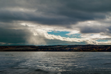 Storm clouds.Rain clouds over the river and forest on the horizon.