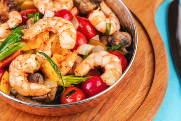 Seafood, Mediterranean cuisine, European dish. Warm salad of grilled fish pieces, shrimps and mussels in a frying pan, with grilled vegetables - with green onions, greens, mushrooms and vegetables.