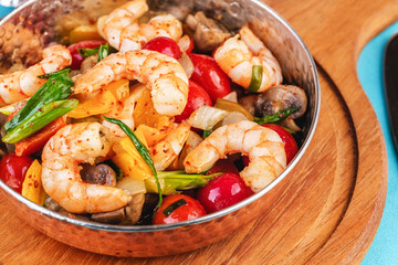 Seafood, Mediterranean cuisine, European dish. Warm salad of grilled fish pieces, shrimps and mussels in a frying pan, with grilled vegetables - with green onions, greens, mushrooms and vegetables.