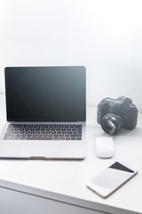 Espacio de trabajo con cámara, portátil y smartphone de un fotógrafo profesional y diseñador gráfico