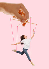 Woman like a puppet in somebodies hands on coral background. Concept of unfair manipulation,...