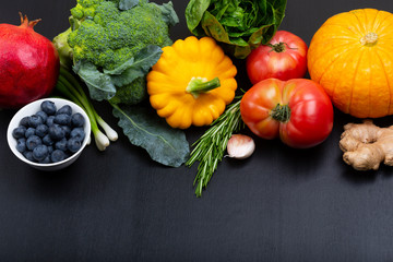 Mix of fresh healthy vegetarian ingredients of vegetables, fruit and berries on a black wooden background. Top view. copy space.