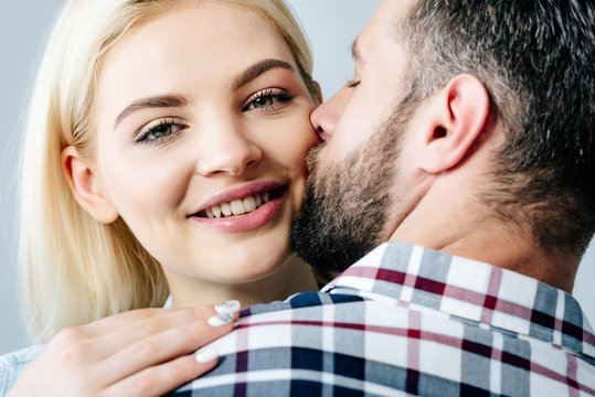 man and happy young woman kissing isolated on grey