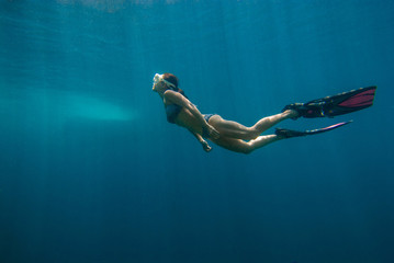 Woman freediver and beautiful light in blue ocean during happy holidays underwater world at the sea...
