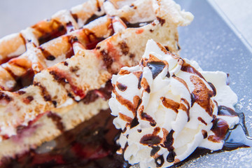 Waffles with whipped cream, cherries and chocolate sauce