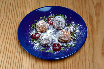 Meat balls with decor on a blue plate on a wooden background