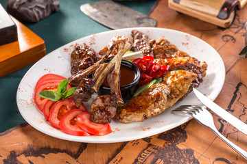 Assorted delicious grilled bbq meat with tomatoes on white plate on old map background