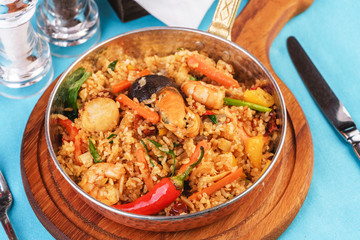 Mediterranean dish, European cuisine. The dish is from Uzbek cuisine. Rice fried with vegetables - greens, carrots, red pepper, onions and seafood - shrimps, mussels and squid.