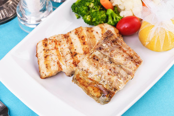 Mediterranean dish, European cuisine. Grilled pieces of fish, served with cooked vegetables -...