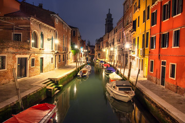Venice cityscape at night, Italy. Venezia city illuminated by lanterns. Venetian canal with boats