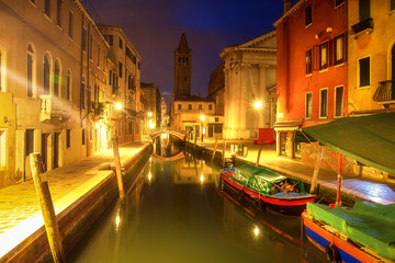 Venice at night, Italy. Beautiful view on narrow venetian canal with boats at night. Venezia illuminated by citylights