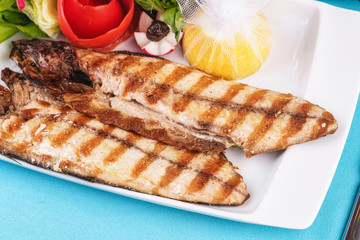 Seafood, Mediterranean cuisine. Grilled Seafood Steak fish with greens, cucumber, lemon and chili. Japanese food