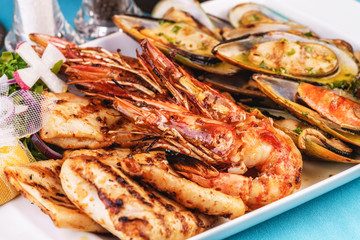 European cuisine, Mediterranean dish. Plate with assorted sea grill. Fried fish, king prawns with lemon, mussels with oyster sauce, colmar rings, crab meat