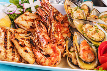 European cuisine, Mediterranean dish. Plate with assorted sea grill. Fried fish, king prawns with lemon, mussels with oyster sauce, colmar rings, crab meat