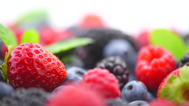 Berries. Various colorful berries background. Strawberry, raspberry, blackberry, blueberry closeup over white. Healthy eating. Rotation. Slow motion 4K UHD video footage. 3840X2160