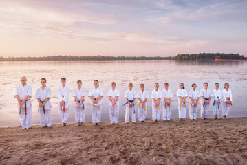 Karate kids team standing on sunset beach