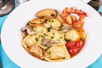 European cuisine, Italian cuisine, Mediterranean dish. Raviolli with fish meat, squid, herbs, tomatoes and shrimps