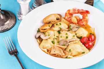 European cuisine, Italian cuisine, Mediterranean dish. Raviolli with fish meat, squid, herbs, tomatoes and shrimps