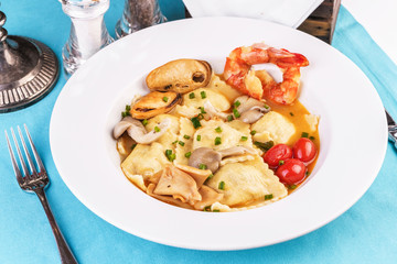 European cuisine, Italian cuisine, Mediterranean dish. Raviolli with fish meat, squid, herbs, tomatoes and shrimps