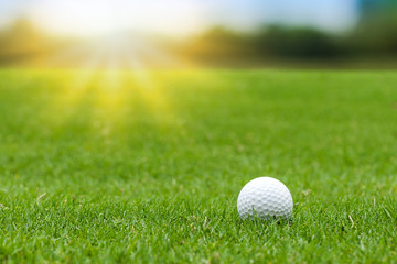 Golf ball on green grass on blurred beautiful landscape of golf course with sunrise,sunset time on...