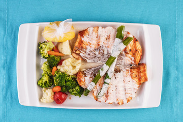 European cuisine, Mediterranean dish. Grilled atrantik salmon steak with cream sauce, served with vegetables and salad