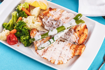 European cuisine, Mediterranean dish. Grilled atrantik salmon steak with cream sauce, served with vegetables and salad