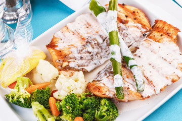 European cuisine, Mediterranean dish. Grilled atrantik salmon steak with cream sauce, served with vegetables and salad
