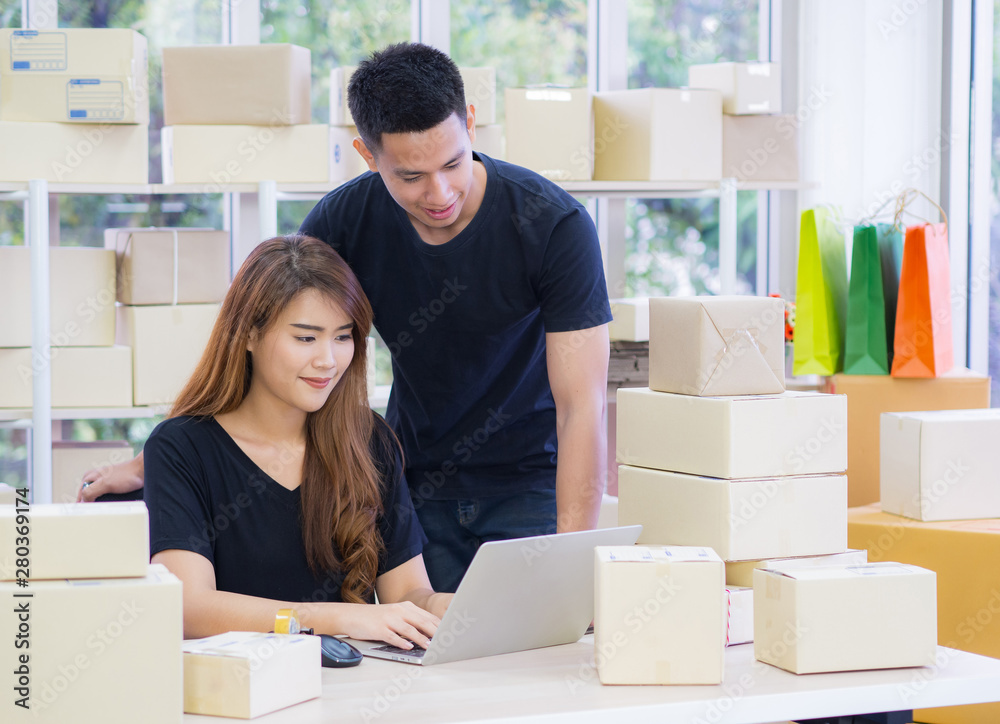 Wall mural Young Asian couple e-commerce business workers at the office