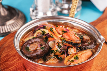 European cuisine, Italian cuisine, Mediterranean dish. Minestrone stew soup with mushrooms, fish meat, squids, mussels, greens, tomatoes and shrimps