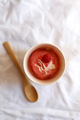 Fototapeta premium Strawberry vegan ice cream, decorated with raspberry and coconut flakes, in colorful paper cup. Top view.