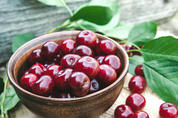 Sweet organic berries in a bowl on old wooden boards.