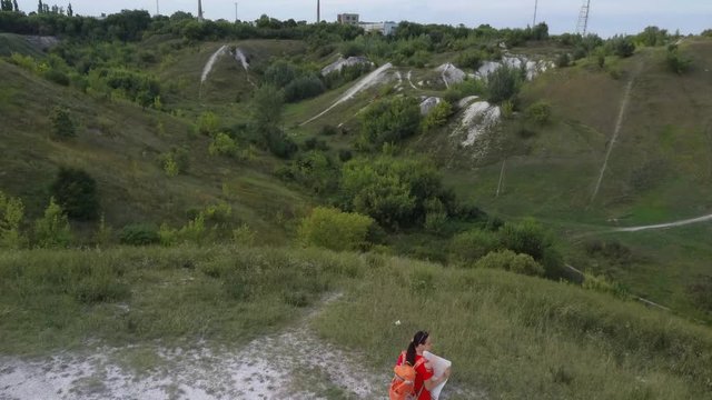 Traveling woman with map in nature. Woman with backpack walking in narrow winding path going through green bushes and trees. Casual woman carrying backpack. Traveler traveling alone