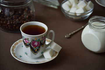 A cup of coffee, milk, sugar cubes.