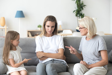 Serious three diverse generation daughter granddaughter and grandmother indoors