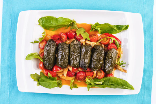 Uzbek cuisine, oriental cuisine. Dolma - Leaves of grapes, boiled rolls with meat, beef and rice. Served with vegetables - tomatoes, peppers, cucumbers and onions