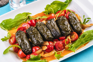 Uzbek cuisine, oriental cuisine. Dolma - Leaves of grapes, boiled rolls with meat, beef and rice. Served with vegetables - tomatoes, peppers, cucumbers and onions
