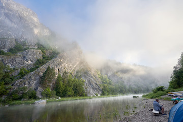 Fototapeta premium Morning fog on the mountain river. Tourist campground in the corner of the frame