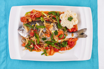 Seafood, Mediterranean cuisine. Baked sea fish with mushrooms, herbs, carrots, millers, cilantro, corn and onions. Caucasian national cuisine