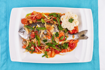 Seafood, Mediterranean cuisine. Baked sea fish with mushrooms, herbs, carrots, millers, cilantro, corn and onions. Caucasian national cuisine